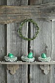 Hand-painted Easter eggs in willow nests on rustic wooden shelf