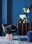 Classic lounge armchair, trumpet next to Siedeboard against blue wall in living room