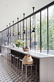 Long, narrow kitchen with concrete counter, cement tiles and glass wall