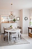 Festively decorated dining table below chandelier in Scandinavian dining room