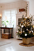 Geschmückter Weihnachtsbaum vor Vitrinenschrank in skandinavischem Esszimmer mit weißem Holzdielenboden
