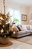 Decorated Christmas tree next to grey sofa in living room