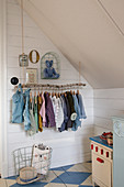 Child's clothes on DIY clothes rack in attic room with blue-and-white chequered floor