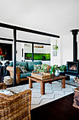 Rustic coffee table in front of fireplace, rattan sofa with overlay in open living room