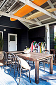 Vintage wooden table with bentwood chairs and surfboard collection on wooden terrace