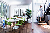 Replica of classic table with lime green chairs in open dining area, woman on stairs