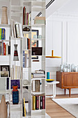 White, metal bookcase used as partition in living room