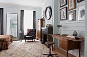 Teal desk, marble fireplace and vintage leather armchair in spacious bedroom