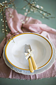 Cutlery with yellow handles on two plates on pink cloth