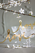 Gold paper lettering reading 'love' in front of old wine glasses