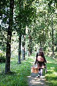 Women carrying picnic basket through trees