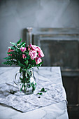 Bunch of pink roses in glass jug on table