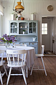 Table, white-painted wooden chairs and dresser in dining room