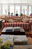 Sofa mit rot-weiß gestreiftem Plaid und geblümten Kissen im Wohnzimmer