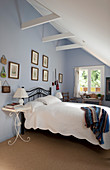 Bed against pale blue wall in attic bedroom with sloping ceiling