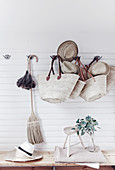 Straw hats, raffia baskets, feather duster and besom broom hung from coat rack