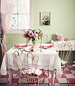 Rosafarbener Blumenstrauss auf rosa-weiss gedecktem Tisch