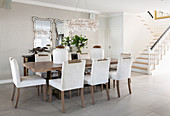 Table, chairs with pale upholstery and Venetian mirrors on wall in elegant dining room