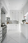 Elegante, weiße Einbauküche mit wabenförmigen Wandfliesen