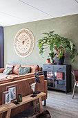 Leather sofas, houseplants on black cabinet and wall hanging with animal skull in living room