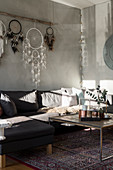 Coffee table, sofa, dreamcatchers on wall, armchair and screen in living room with pale grey walls