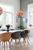 Table and shell chairs below copper pendant lamp in bright dining room