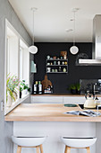 View over counter with pale wooden surface to kitchen counter against charcoal wall
