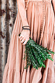 Frau im nostalgischen Kleid hält einen Bund Rosmarinzweige in der Hand