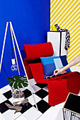 Hand puts sunglasses on red designer armchair against blue wall