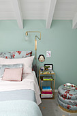 Doppelbett im Schlafzimmer mit mintfarbener Wand und weiß gestrichener Holzdecke