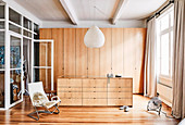 Spacious dressing area with wardrobe and chest of drawers made of light wood