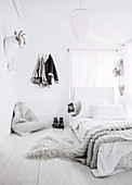 Feminines Schlafzimmer in Weiß mit Sitzsack und märchenhaften Tiertrophäen als Wanddeko