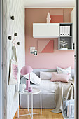 Daybed and side table in room with pink, pale grey and white accessories