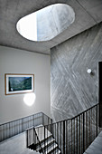 Stairwell with metal banisters, skylight and concrete wall
