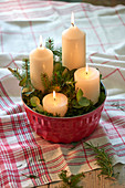 Vier weiße Kerzen in einer Gugelhupfform mit Zweigen