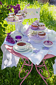 Table set with muffins, tea and lilac in garden