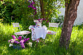 Set table, chairs and tub of lilac in garden