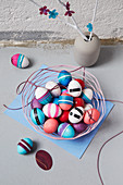 Basket of Easter eggs and branches decorated with paper flowers in vase