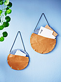 Round leather and felt storage bags on a light blue wall