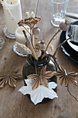 Dried flowers in vase, poppy seed heads and origami maple leaves
