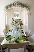 Table festively set with green accessories in front of archway