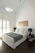Double bed and black table lamps on bedside tables in white bedroom