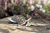 Teaspoon with sprigs of heather and viola flower