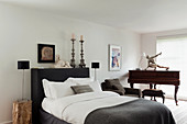 Klavier im geräumigen Schlafzimmer mit Doppelbett, Kerzenhalter und Sphinxstatue auf Ablage