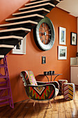 Kilim chair under a self-supporting staircase against orange wall