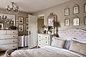 Antique double bed with headboard, chests of drawers and botanical drawings on bedroom walls