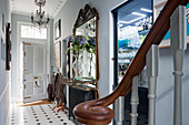 Custom-built mirrored bar in entrance hall with tiled flooring, chanderlier and large gilt framed mirror