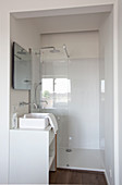 White washstand with countertop sink and shower area in small bathroom