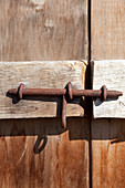 Rusty metal bolt on wooden door in sunshine