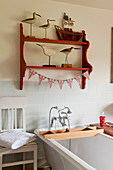 Wooden bird statues on red shelf in bathroom with decorative union jack bunting